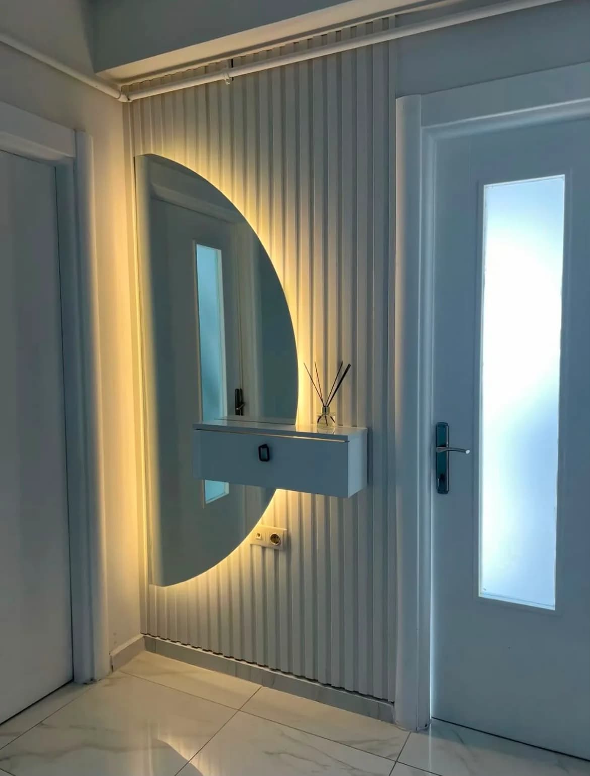 Beyaz çıtalı antre duvarında yarım daire ayna ve askıda dresuar