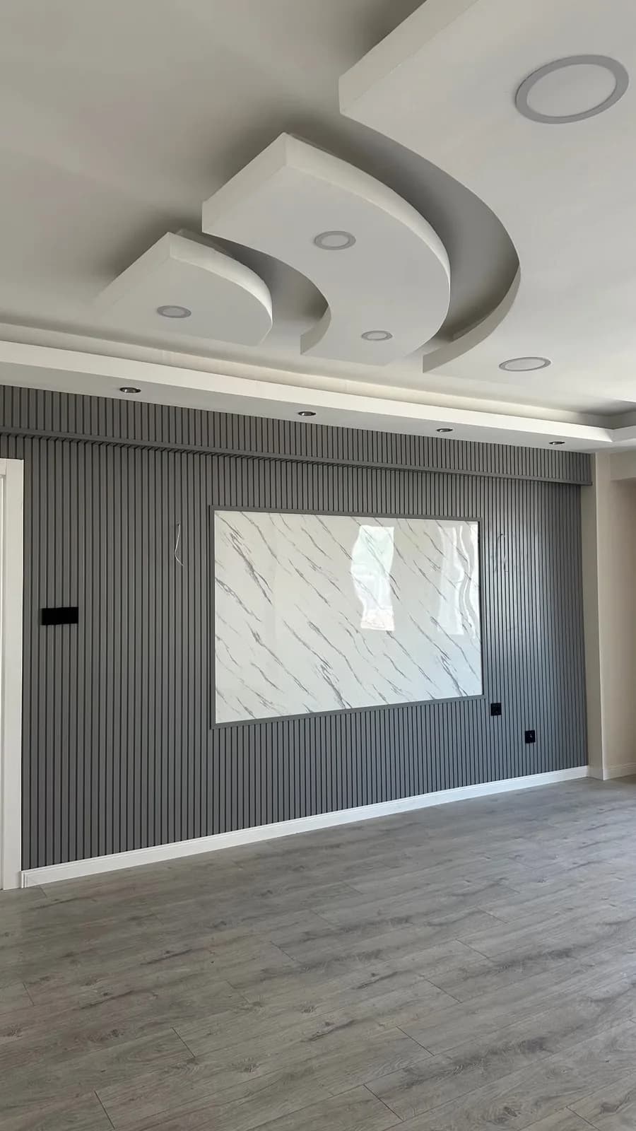 Koyu çıta panel ve mermer desenli TV duvarı, LED aydınlatma